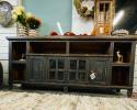 Wooden TV stand with cut out holes in the back for cords. Shelf the length of cabinet for your components and 4 doors with shelves behind them for movies and board games. The middle two doors have glass in them and it is all accented with rustic iron hardware.