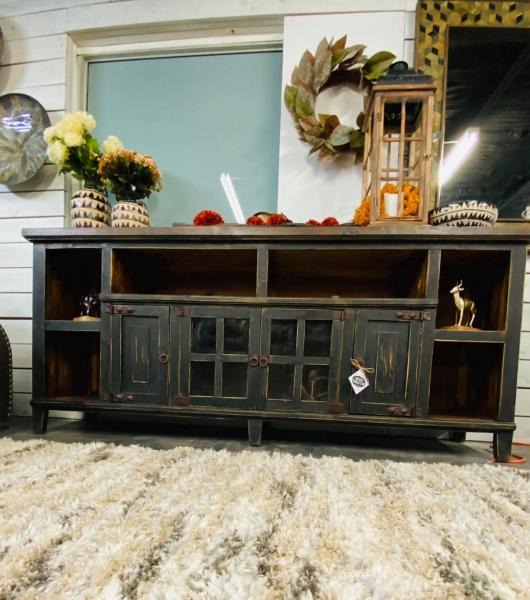 Wooden TV stand with cut out holes in the back for cords. Shelf the length of cabinet for your components and 4 doors with shelves behind them for movies and board games. The middle two doors have glass in them and it is all accented with rustic iron hardware.